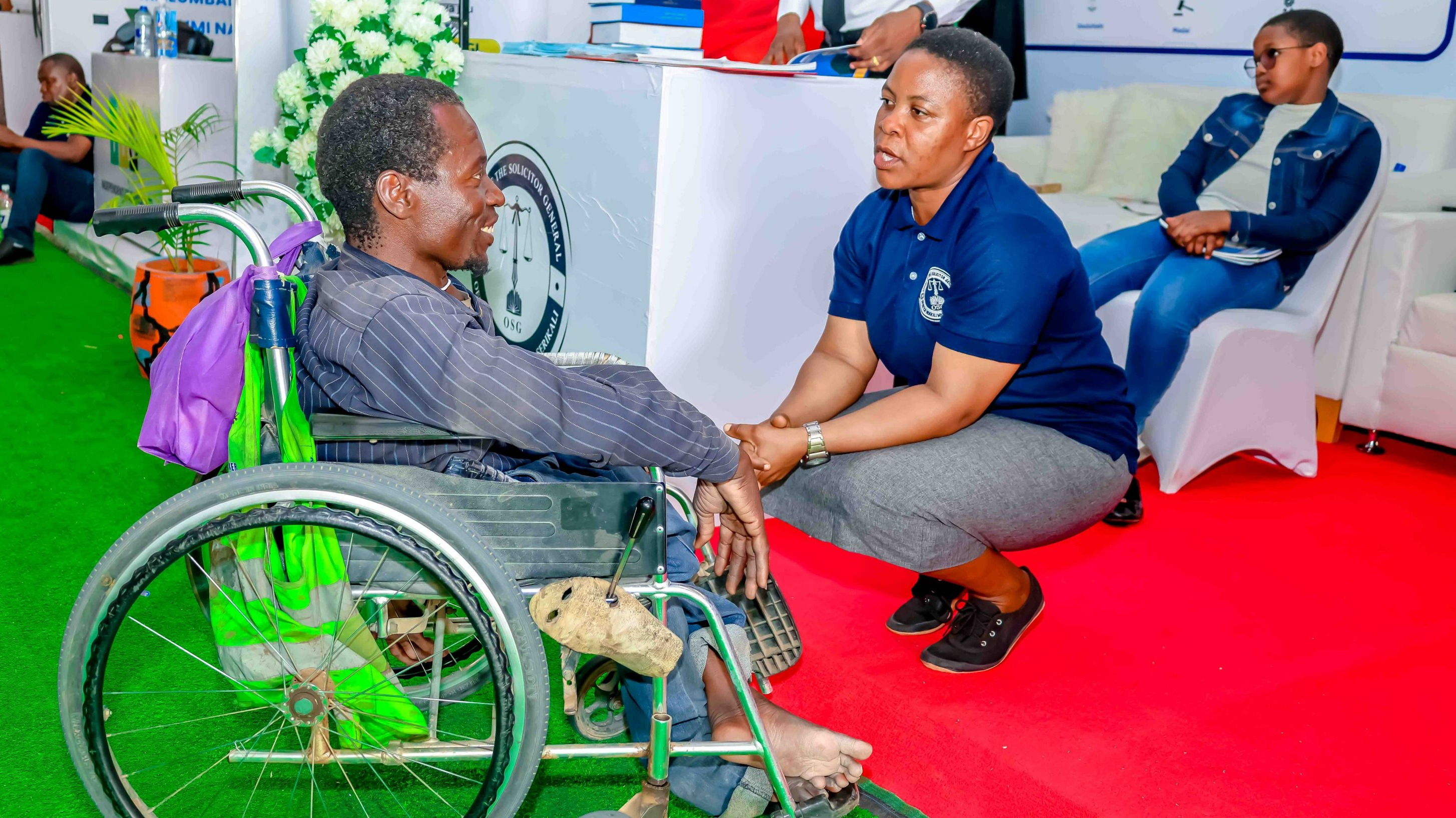 Wakili wa Serikali wa Ofisi ya Wakili Mkuu wa Serikali, Bi. Kumbukeni Kondo akimsilikiza mwananchi mwenye mahitaji maalumu ndugu Semeni Lutaja alipotembelea banda la Ofisi hiyo wakati wa maonesho ya Nanenane yaliyofanyika kwenye viwanja vya Maonesho vya Dkt. John Samuel Malecela, Jijini Dodoma.